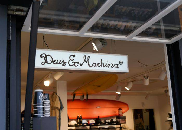 Looking through the open door of Deus Ex Machina, showing coffee cups, surfboards and Deus Ex Machina-branded hats.